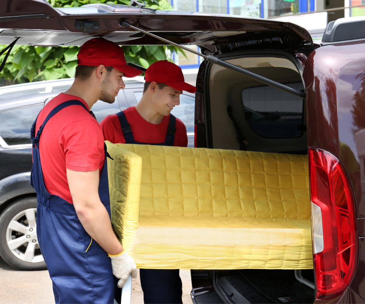 Umzugshelfer laden ein gelbes Sofa in einen Transporter – Preiswert umziehen Königstein