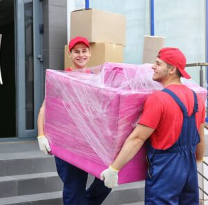 Umzug in Königstein Zwei Umzugshelfer tragen ein in Folie gepacktes Möbelstück – Umzug in Königstein