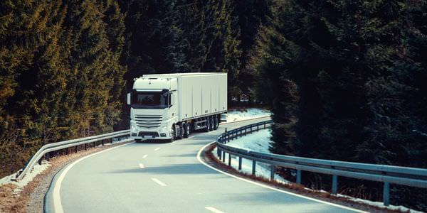 Klaviertransport Königstein: Lkw fährt auf einer kurvigen Straße durch den Wald